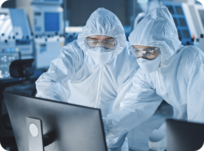 Two people in full protective gear in a lab looking at a computer